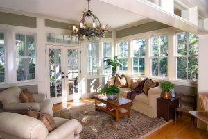 A spacious sunroom with a comfortable beige sofa and armchairs.