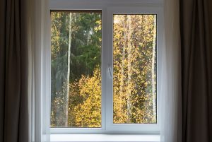 Close-up view of a white casement window framed with brown drapes