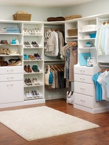 White closet system with neatly arranged colthes and accesories.